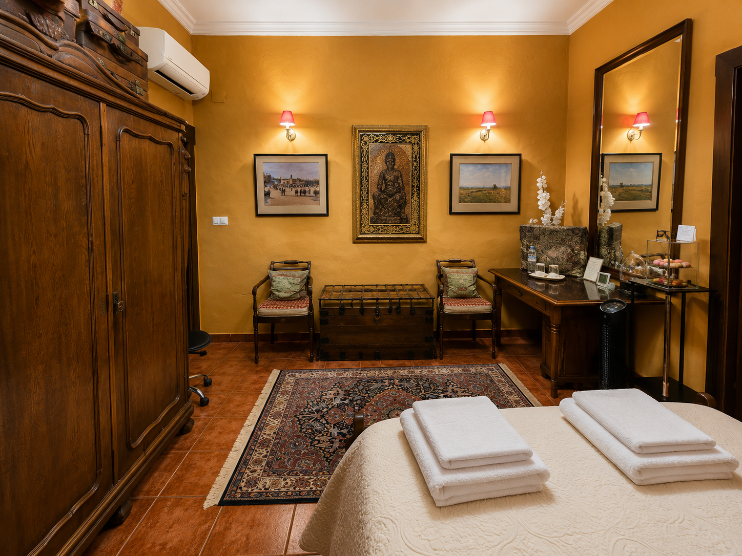 Habitación Esencia — rincón con butacas, baúl antiguo y obras enmarcadas