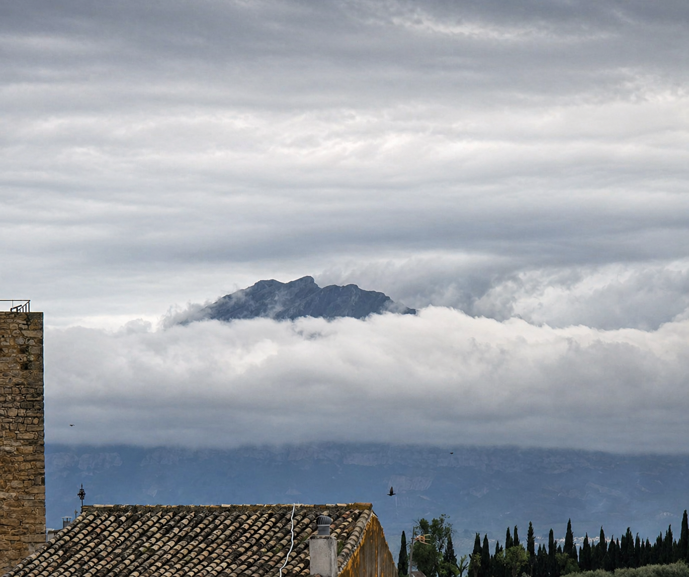 Sierra Mágina emergiendo entre nubes sobre los tejados de Begíjar